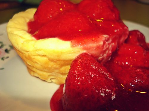 Ein kleiner Käsekuchen aus der Muffinform mit fruchtiger Erdbeersoße