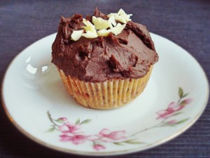 Fluffig gebackener Cupcake mit Schokostückchen und Kirschen im Teig und einem schokoladigen Frosting on Top