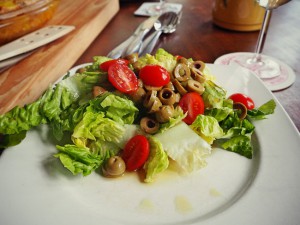 Der Salat zur Tortilla mit Oliven, Tomaten und einem Sherryessig-Öl-Dressing